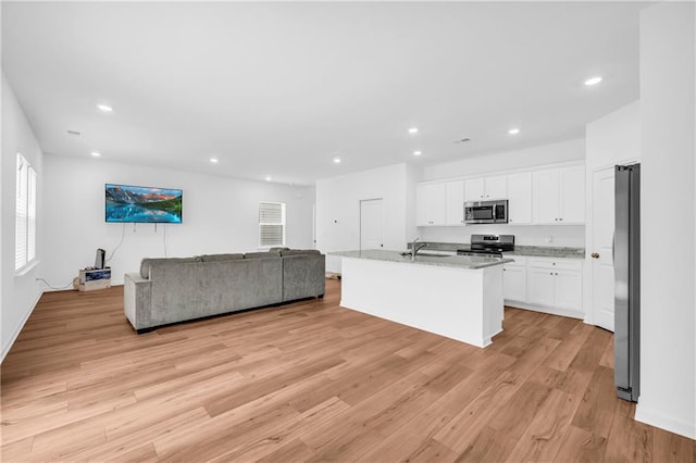 kitchen with a sink, appliances with stainless steel finishes, recessed lighting, and open floor plan