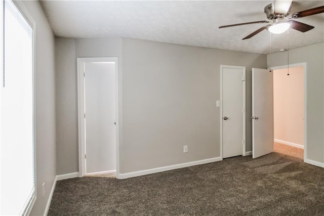 unfurnished bedroom featuring dark colored carpet, multiple windows, and ceiling fan