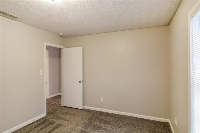 carpeted empty room featuring a textured ceiling