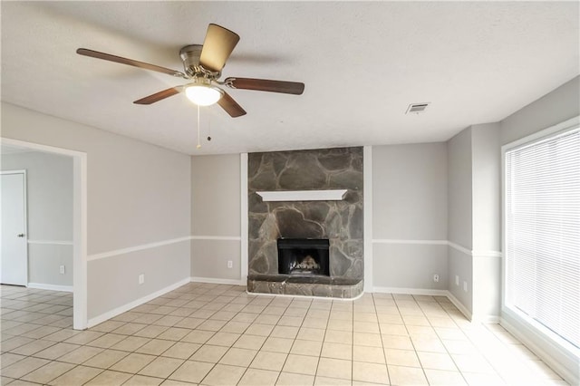 unfurnished living room with ceiling fan and a stone fireplace