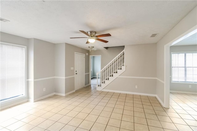 tiled spare room with ceiling fan and a textured ceiling