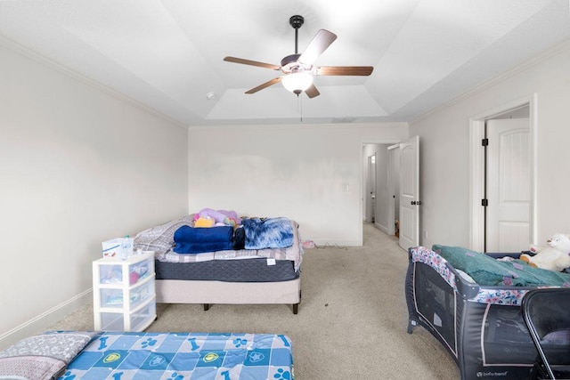 carpeted bedroom with a tray ceiling, crown molding, and baseboards