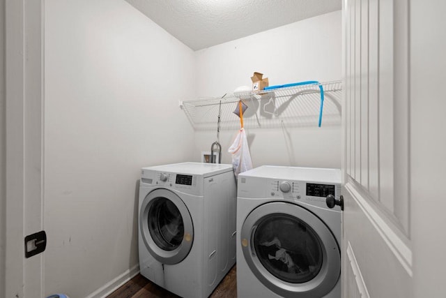 clothes washing area with dark wood-style flooring, laundry area, a textured ceiling, baseboards, and washing machine and dryer
