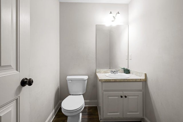 bathroom with toilet, baseboards, vanity, and wood finished floors