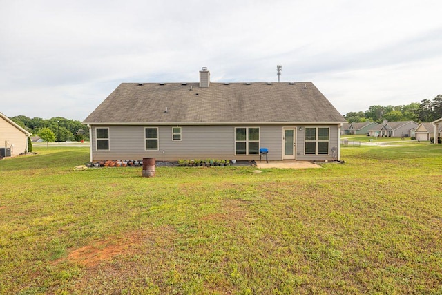 rear view of property featuring a yard, a chimney, and a patio area