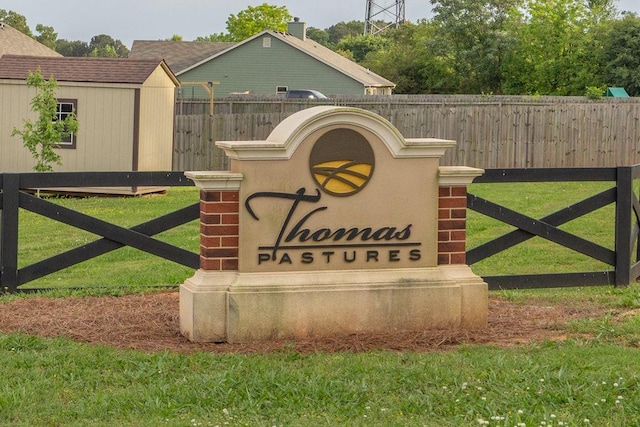 community / neighborhood sign featuring a lawn and fence