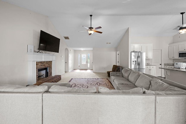 living area with a ceiling fan, high vaulted ceiling, a brick fireplace, visible vents, and light colored carpet