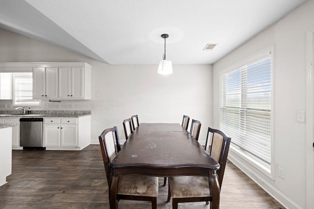 dining space featuring dark wood-style flooring, lofted ceiling, a wealth of natural light, and visible vents
