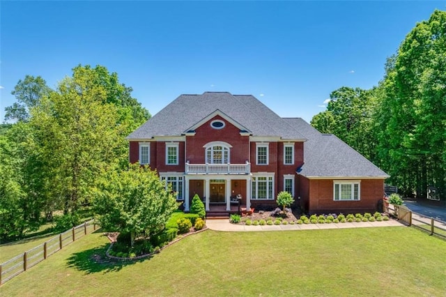 colonial home with a balcony and a front lawn