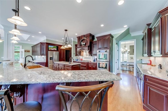 kitchen featuring appliances with stainless steel finishes, hanging light fixtures, a large island, decorative backsplash, and sink