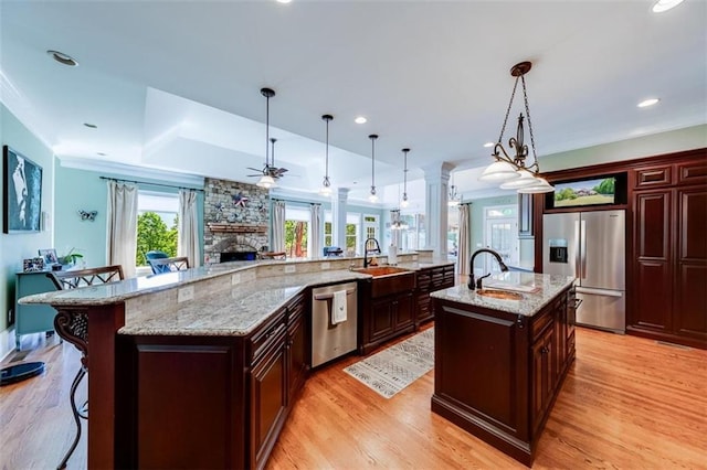 kitchen with pendant lighting, appliances with stainless steel finishes, sink, a large island, and a breakfast bar area