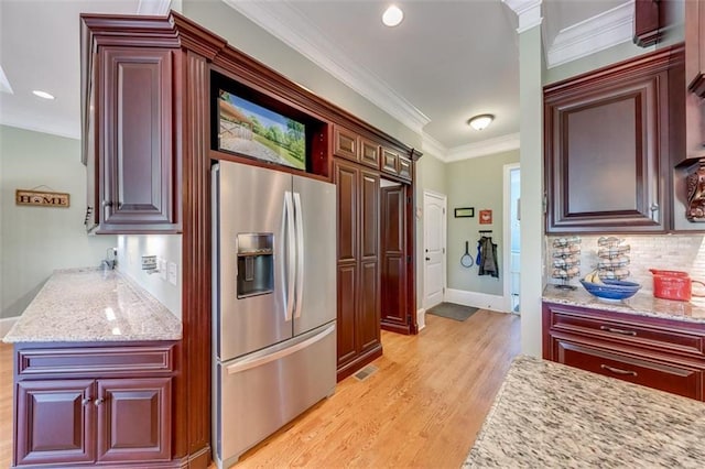 kitchen with stainless steel refrigerator with ice dispenser, light stone countertops, light hardwood / wood-style flooring, and crown molding