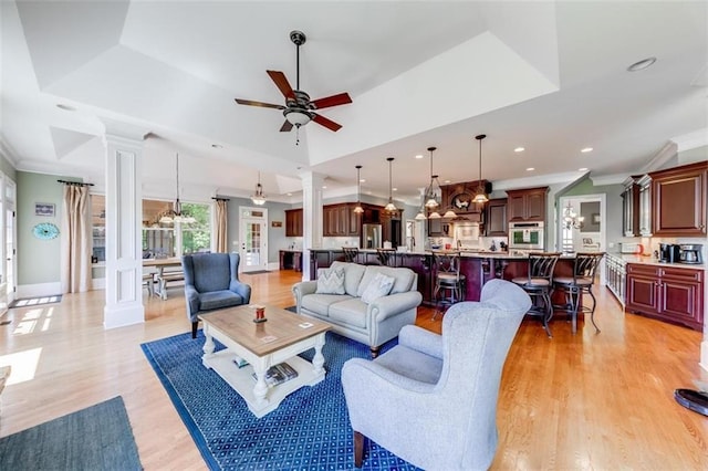 living room with decorative columns, light hardwood / wood-style flooring, and a raised ceiling