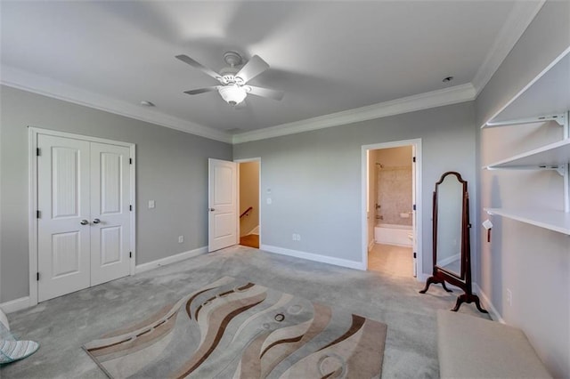 carpeted bedroom featuring a closet, ensuite bath, ceiling fan, and ornamental molding