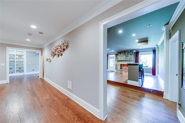 hall featuring built in shelves, wood-type flooring, and ornamental molding