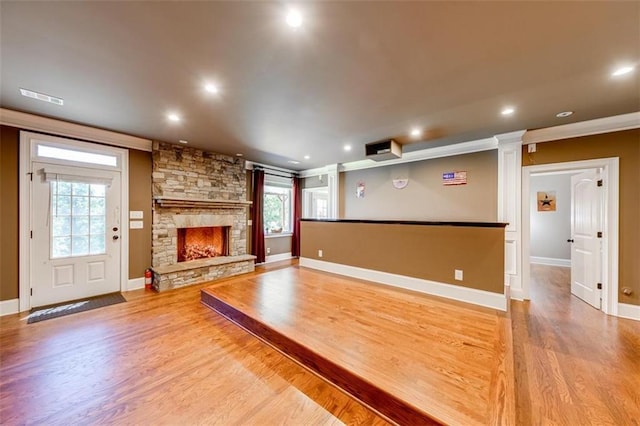 unfurnished living room with a fireplace, hardwood / wood-style flooring, plenty of natural light, and ornate columns