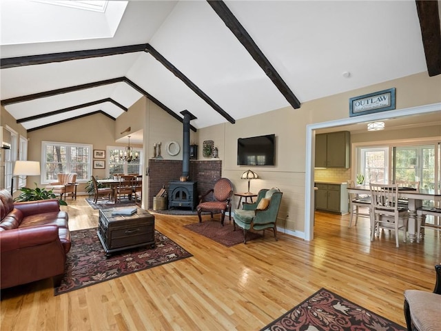 living area featuring beamed ceiling, high vaulted ceiling, a notable chandelier, wood finished floors, and a wood stove