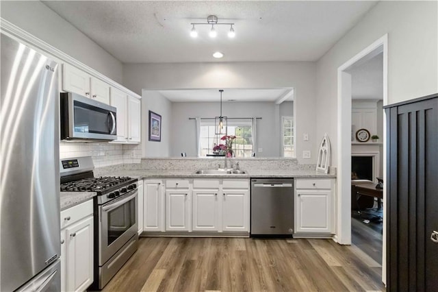 113 Regent Pl, Woodstock, GA 30188 - kitchen featuring stainless steel appliances, a sink, light wood finished floors, white cabinets, and light stone counters