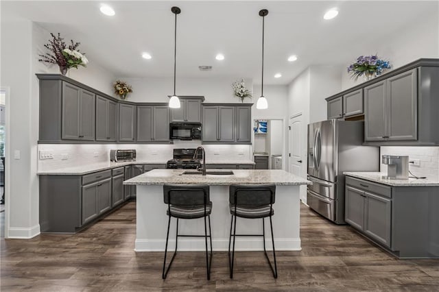 kitchen featuring a center island with sink, dark wood-style floors, light stone countertops, gray cabinets, and black appliances