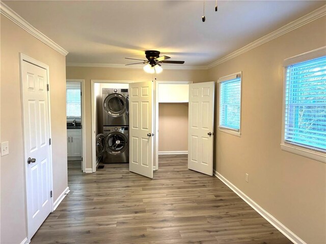 unfurnished bedroom with dark wood-type flooring, stacked washing maching and dryer, multiple windows, and crown molding