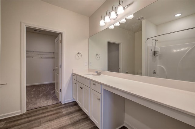 bathroom with walk in shower, vanity, and wood-type flooring