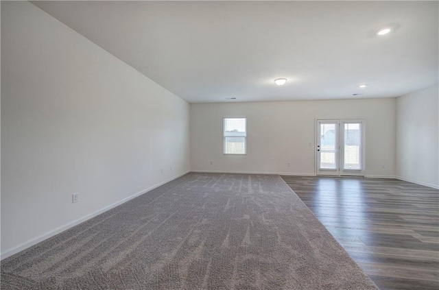 empty room with dark hardwood / wood-style floors and a healthy amount of sunlight