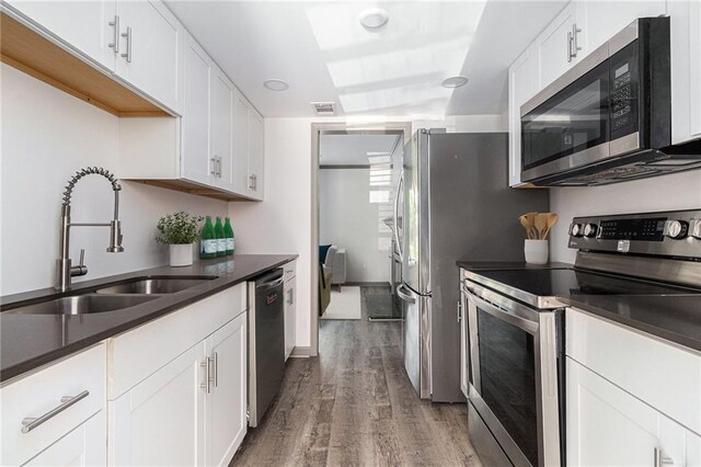 26 Ivy Pkwy NE, Atlanta, GA 30342 - kitchen with stainless steel appliances, a sink, wood finished floors, white cabinets, and dark countertops