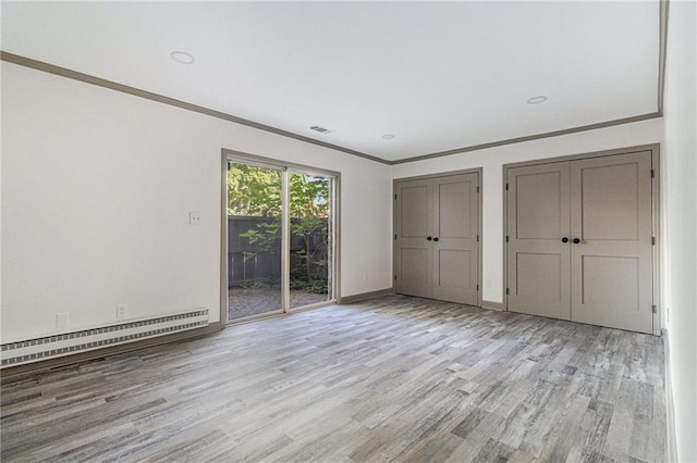 26 Ivy Pkwy NE, Atlanta, GA 30342 - unfurnished bedroom featuring a baseboard heating unit, access to outside, wood finished floors, crown molding, and two closets