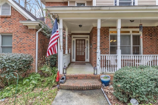 entrance to property featuring brick siding and covered porch