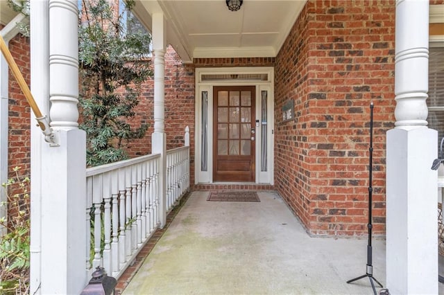 property entrance featuring brick siding and covered porch