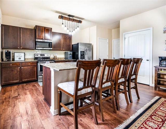 8553 Braylen Manor Dr, Douglasville, GA 30134 - kitchen with stainless steel appliances, dark wood-style floors, a breakfast bar, and a kitchen island