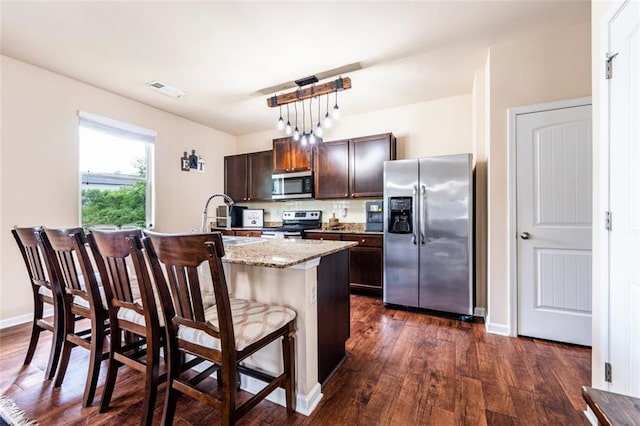 8553 Braylen Manor Dr, Douglasville, GA 30134 - kitchen featuring stainless steel appliances, a sink, dark wood-style flooring, dark brown cabinets, and a kitchen bar