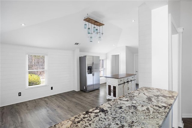 kitchen featuring visible vents, dark stone countertops, stainless steel fridge, dark wood-style flooring, and vaulted ceiling