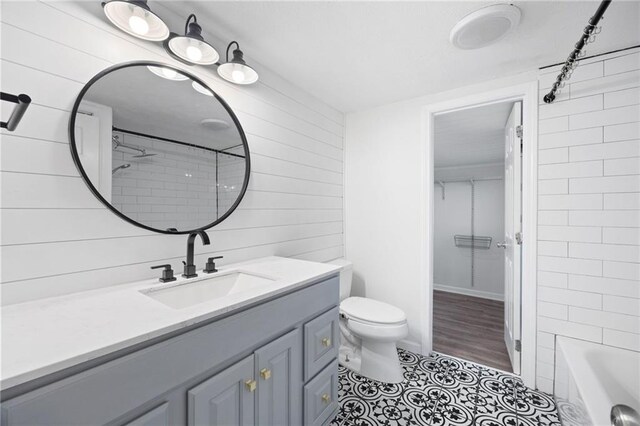 bathroom with tile patterned floors, wooden walls, toilet, and vanity