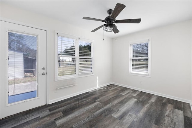 empty room with a wealth of natural light, baseboards, dark wood finished floors, and a ceiling fan