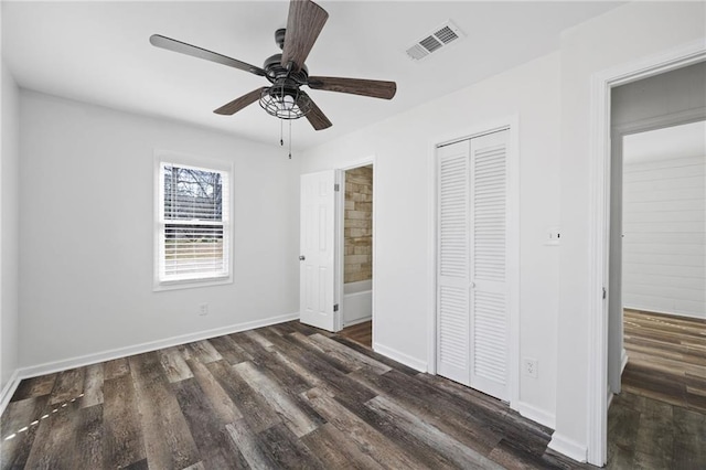 unfurnished bedroom with visible vents, baseboards, a closet, ensuite bathroom, and dark wood-style floors