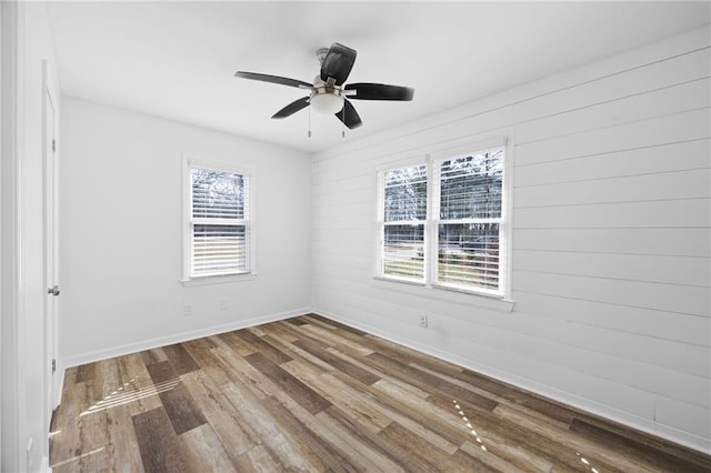 empty room featuring a healthy amount of sunlight, baseboards, ceiling fan, and wood finished floors