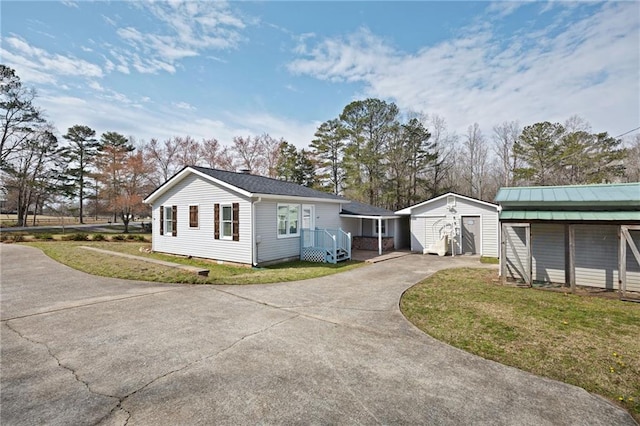 view of property exterior with a garage, an outbuilding, concrete driveway, and a yard