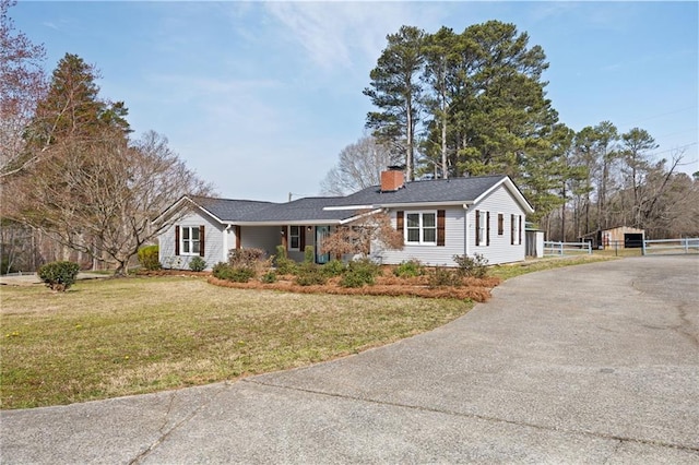 ranch-style house featuring aphalt driveway, a chimney, and a front lawn