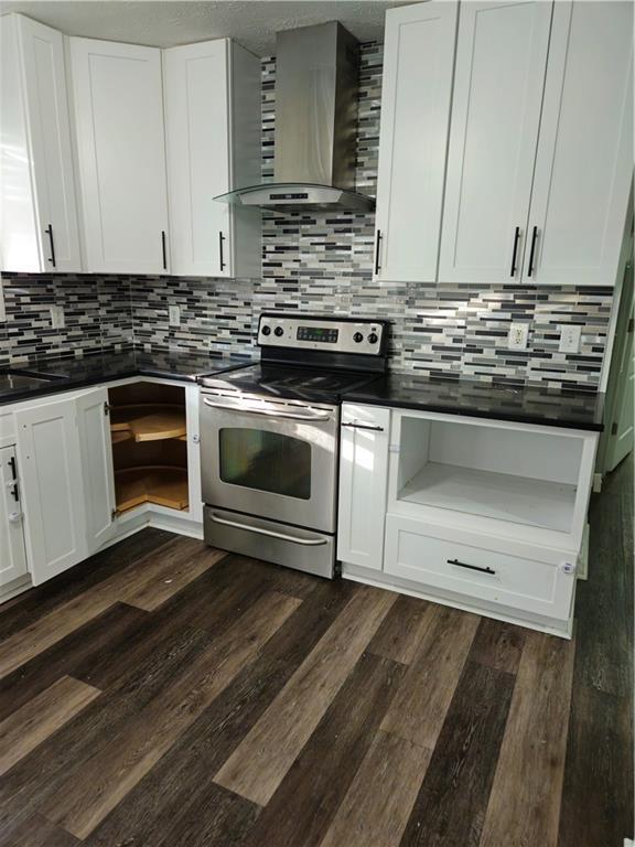 kitchen with dark countertops, stainless steel electric range, wall chimney exhaust hood, and dark wood-style flooring