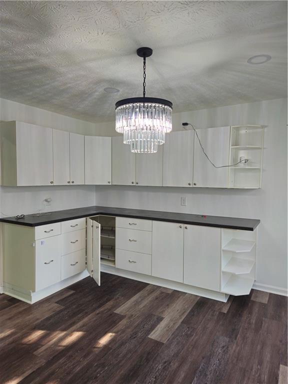 kitchen with dark countertops, dark wood-style flooring, a textured ceiling, and open shelves