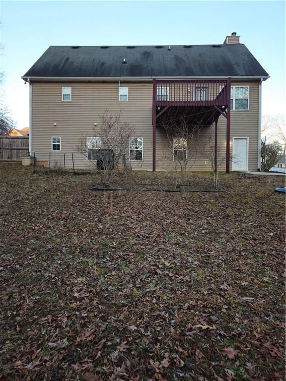 rear view of house featuring fence, a chimney, and a wooden deck