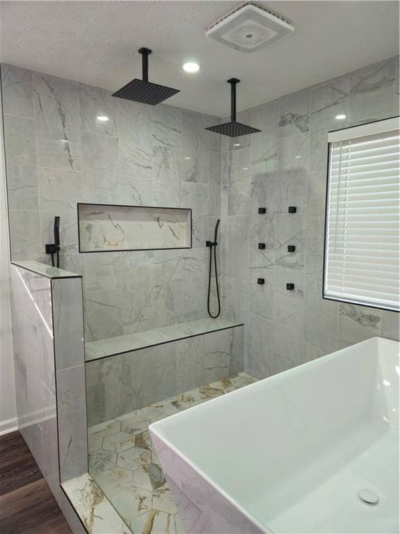 bathroom featuring a textured ceiling, a freestanding tub, wood finished floors, and walk in shower