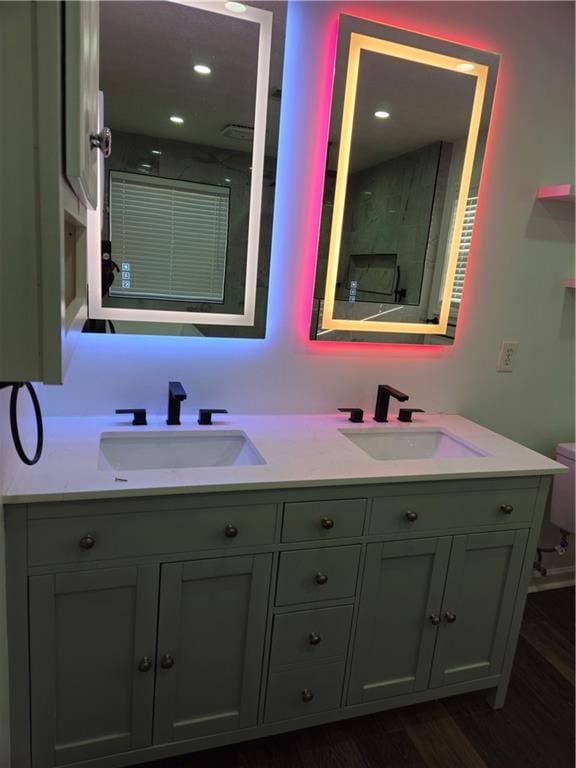 full bath with double vanity, toilet, wood finished floors, and a sink