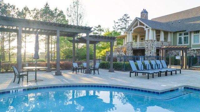 community pool with a patio area, a pergola, and fence