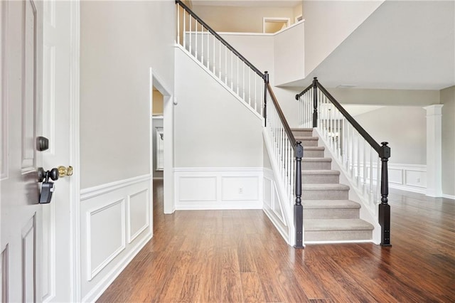 stairway with a towering ceiling and hardwood / wood-style flooring