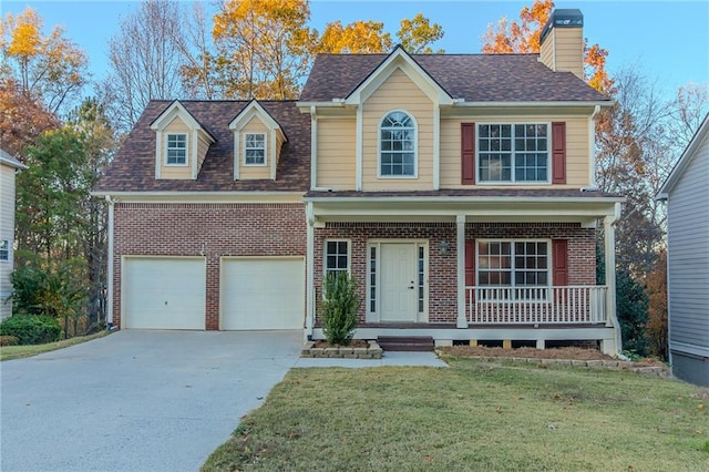 view of front of home featuring covered porch, a garage, and a front yard