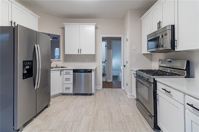 kitchen with appliances with stainless steel finishes, white cabinetry, ceiling fan, and sink