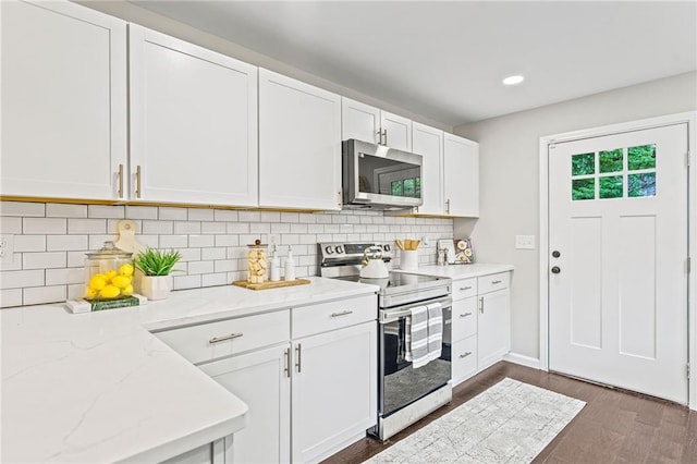 kitchen with stainless steel appliances, white cabinetry, decorative backsplash, light stone countertops, and dark wood-style floors