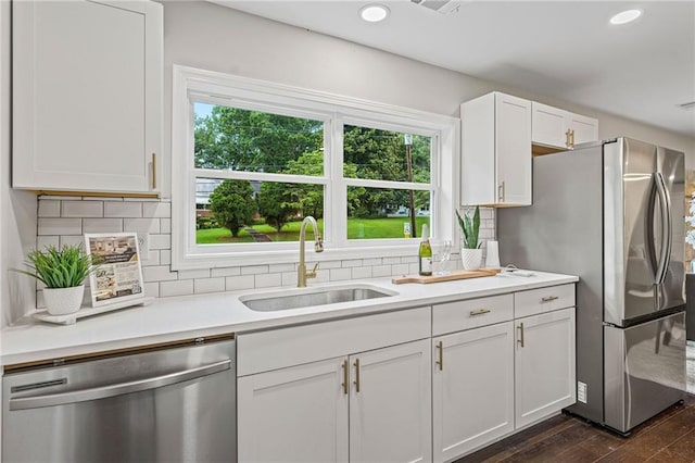 kitchen with stainless steel appliances, light countertops, a sink, and white cabinetry